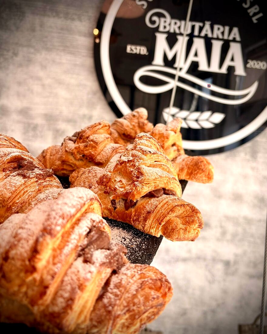 Croissante proaspete în fața siglei rotunde Brutăria Maia