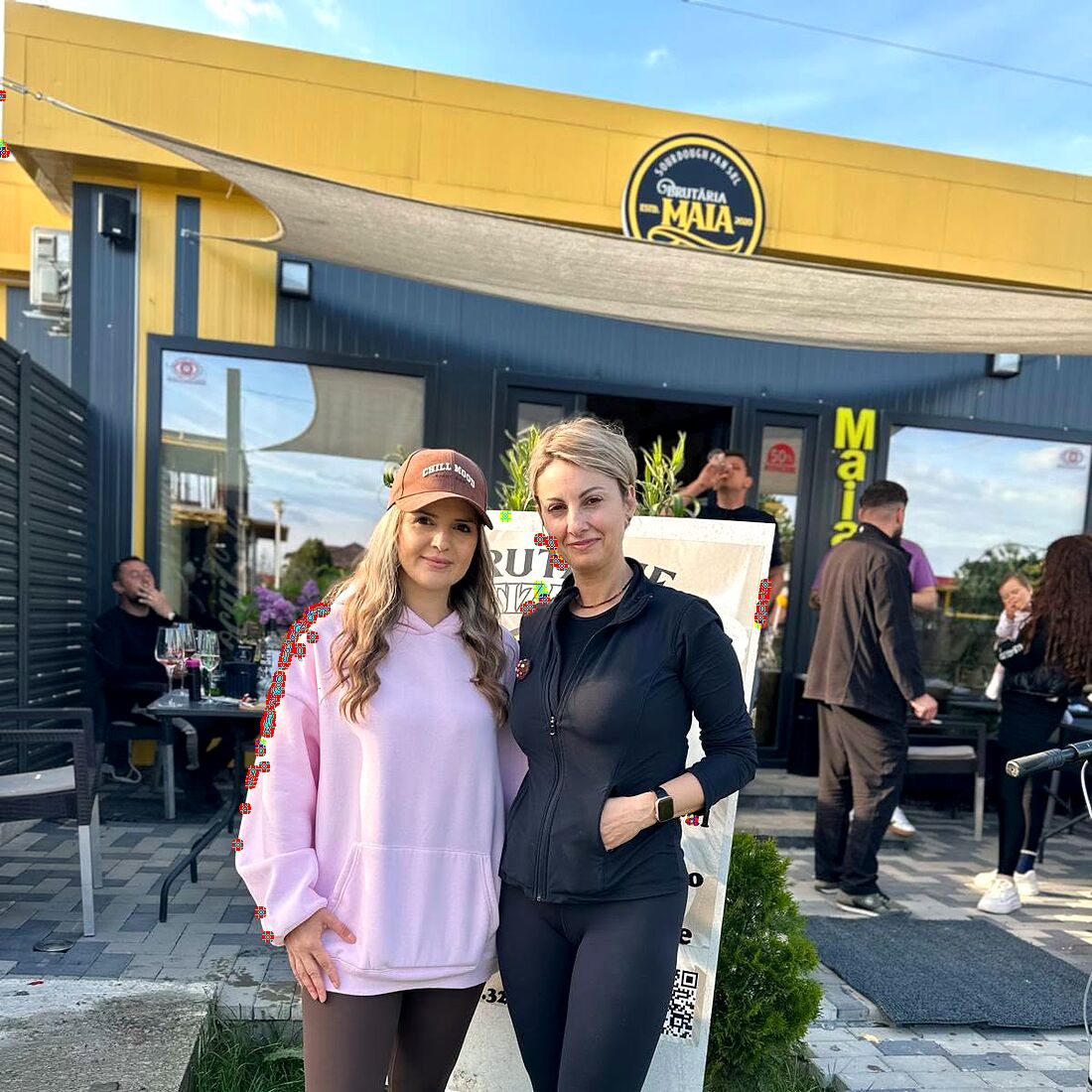 Brutăria Maia din Lumina: clădirea cu firma galbenă și sigla rotundă, cu terasa plină în fața intrării